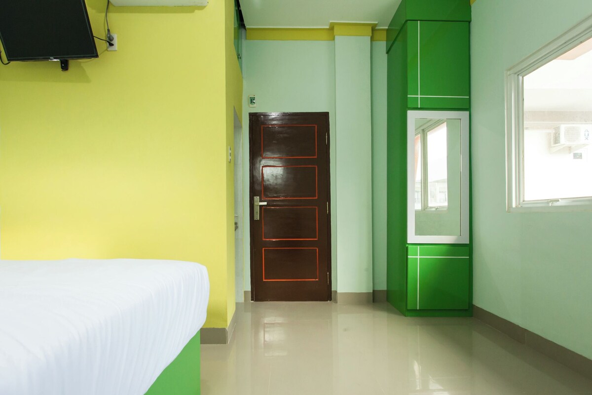 A hotel room with a bed, a door, and a window.