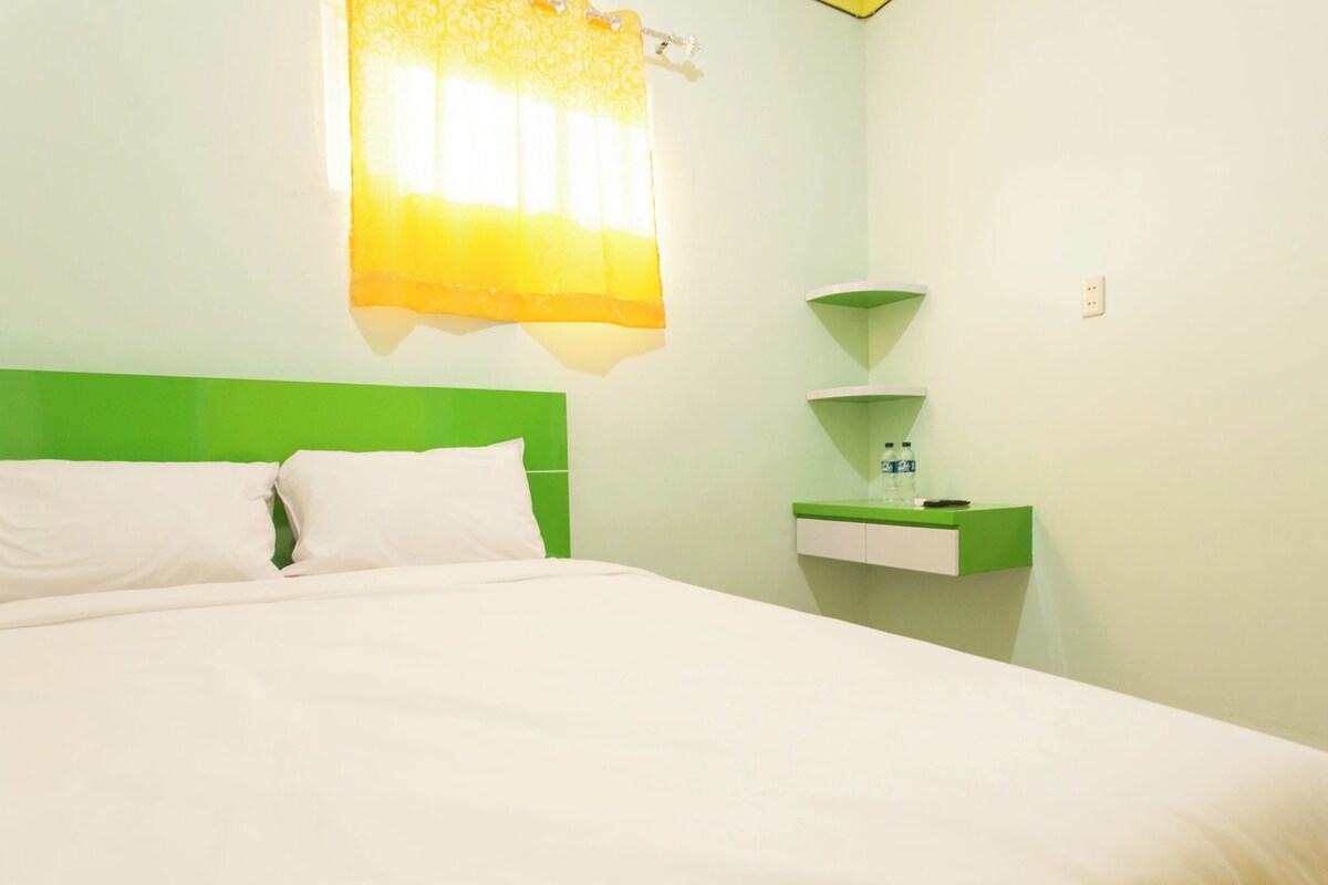 A hotel room with a bed, a nightstand, and a wall-mounted shelf.