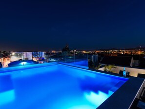 En pool på taket med utsikt över stadens silhuett i nattljuset.