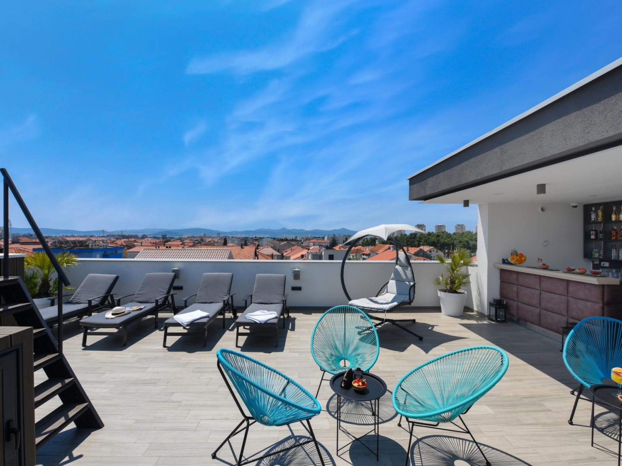 Een dak terras met lounge stoelen, een bar en uitzicht op de stad.