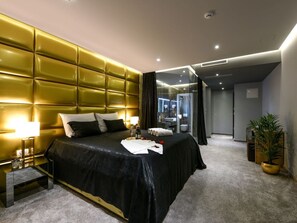 Ett modernt hotellrum med en stor säng, ett sängbord, en liten avlastningsyta, en spegel och en krukväxt.