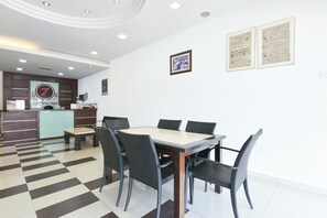 A hotel lobby with a check-in counter, a reception desk, a dining area with a table and chairs, and framed certificates on the wall. - Hotel O KB Near Siti Khadijah Market (Kota Bharu)