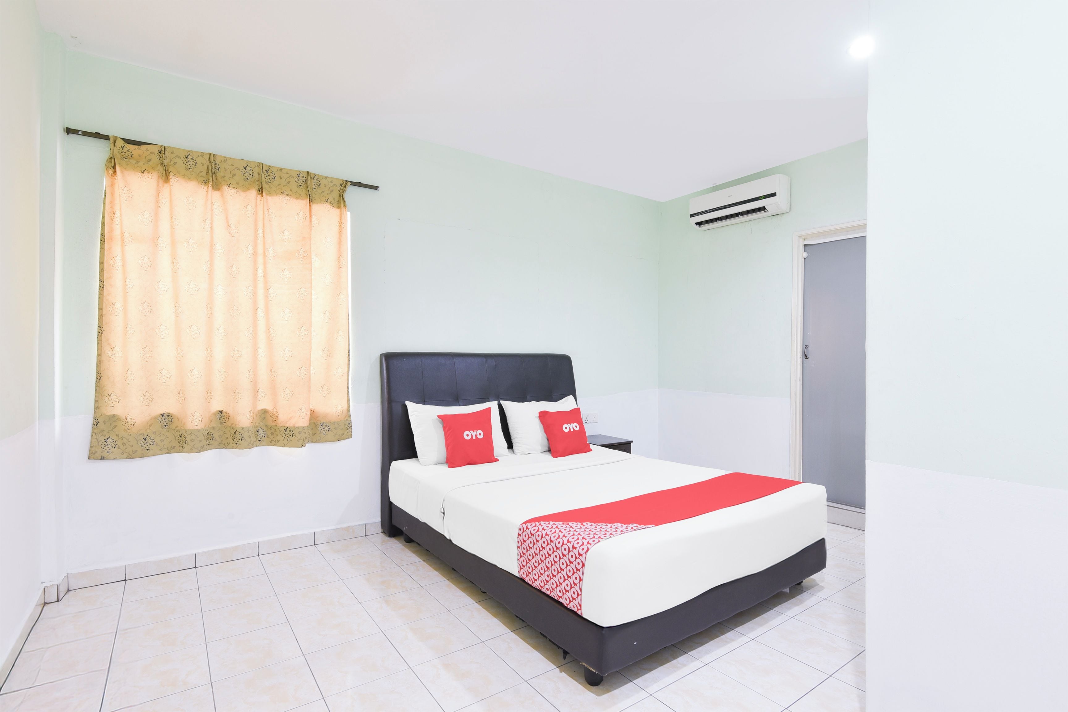 A neatly arranged bedroom with a bed, curtains, and an air conditioning unit.