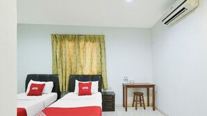 A hotel room with two beds, a desk, a chair, and an air conditioning unit.