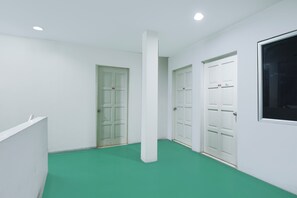 Un pasillo con paredes blancas, alfombra verde y puertas blancas.