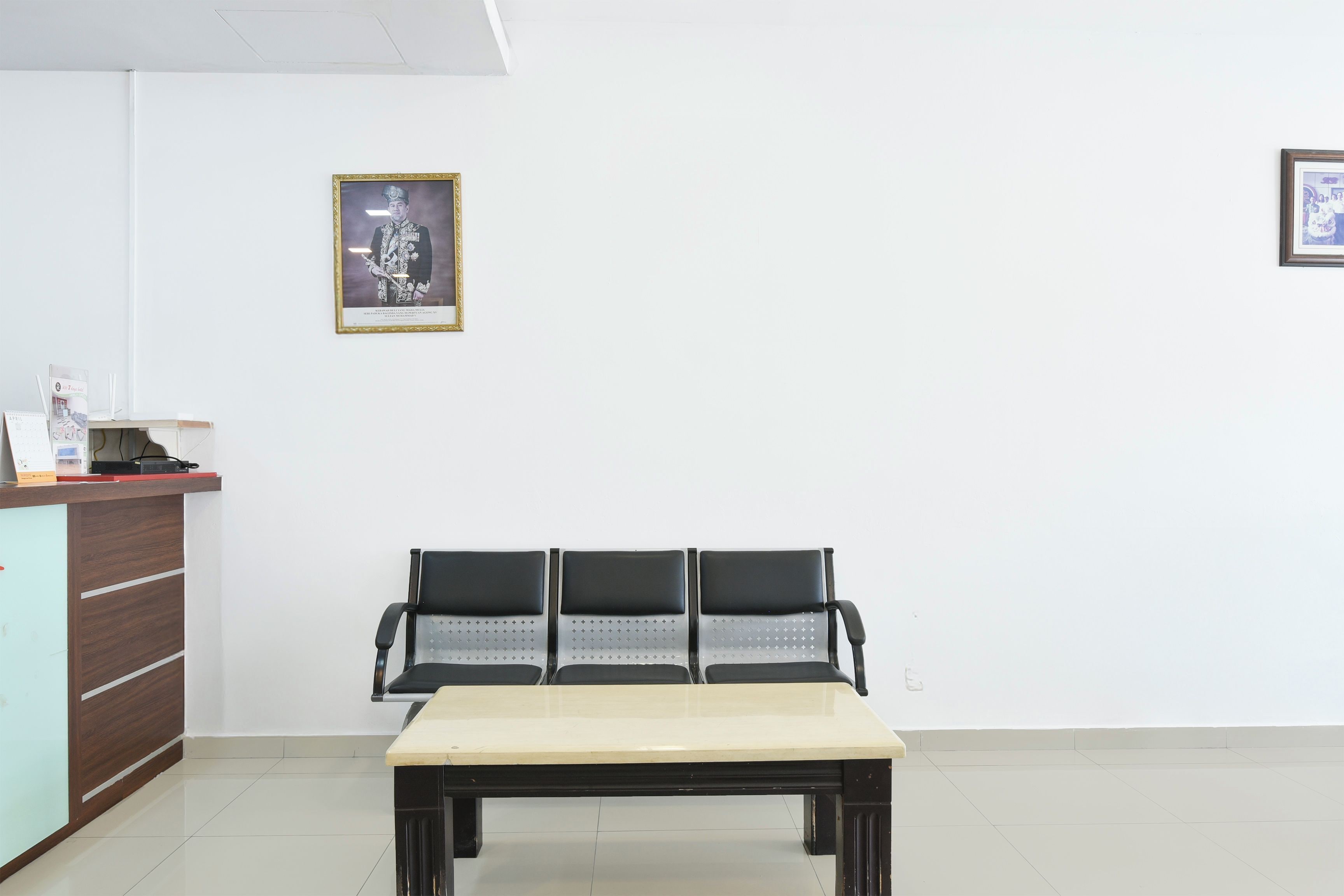 Una zona de recepción con un mostrador, un banco y cuadros en la pared.