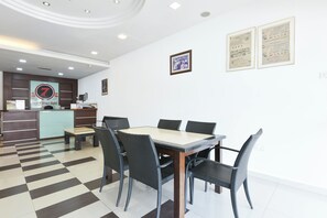 Habitación de hotel con piso de cuadros, una mesa de comedor con sillas, una recepción y certificados enmarcados en la pared.