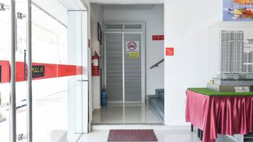 A hotel entrance with a fire extinguisher, a no smoking sign, and a glass door leading to a stairway.