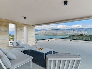 Un espace extérieur moderne, aménagé pour se détendre, avec vue sur un paysage montagneux et un plan d’eau.