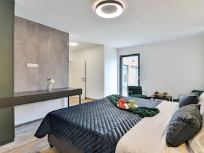 Une chambre à coucher moderne avec un lit, une table de chevet et une vue sur l’extérieur.