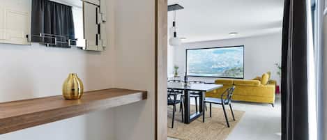 A modern kitchen with a built-in oven, a dining area with a table and chairs, and a large window with a view of a snowy landscape.
