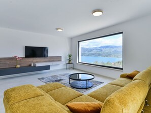 A modern living room with a large window, a flat-screen TV, and a sofa. - Villa Zariva with pool and panoramic mountain and by Interhome (Vinjerac)