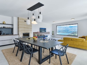 A modern kitchen with a dining area, a large window with a cityscape view, and a yellow sofa in the living room. - Villa Zariva with pool and panoramic mountain and by Interhome (Vinjerac)