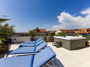 Eine Dachterrasse mit Liegestühlen, einem Whirlpool und Blumentöpfen.