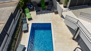 Piscina no terraço com espreguiçadeiras e área de estar.