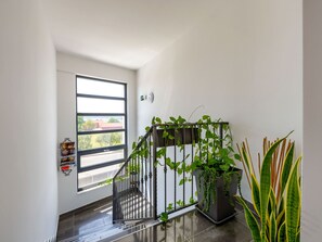A staircase with a metal railing, a potted plant, and a window with a view of buildings.
