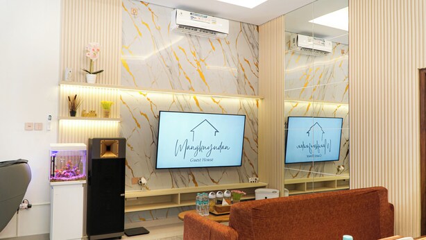 A modern guest room with a large mirror, two televisions, a speaker, and a small aquarium. - D' Mangkuyudan Luxury Guest House (Yogyakarta)