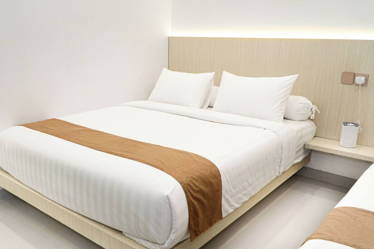 Ein modernes Hotelzimmer mit Bett, Nachttisch und Beistelltisch.