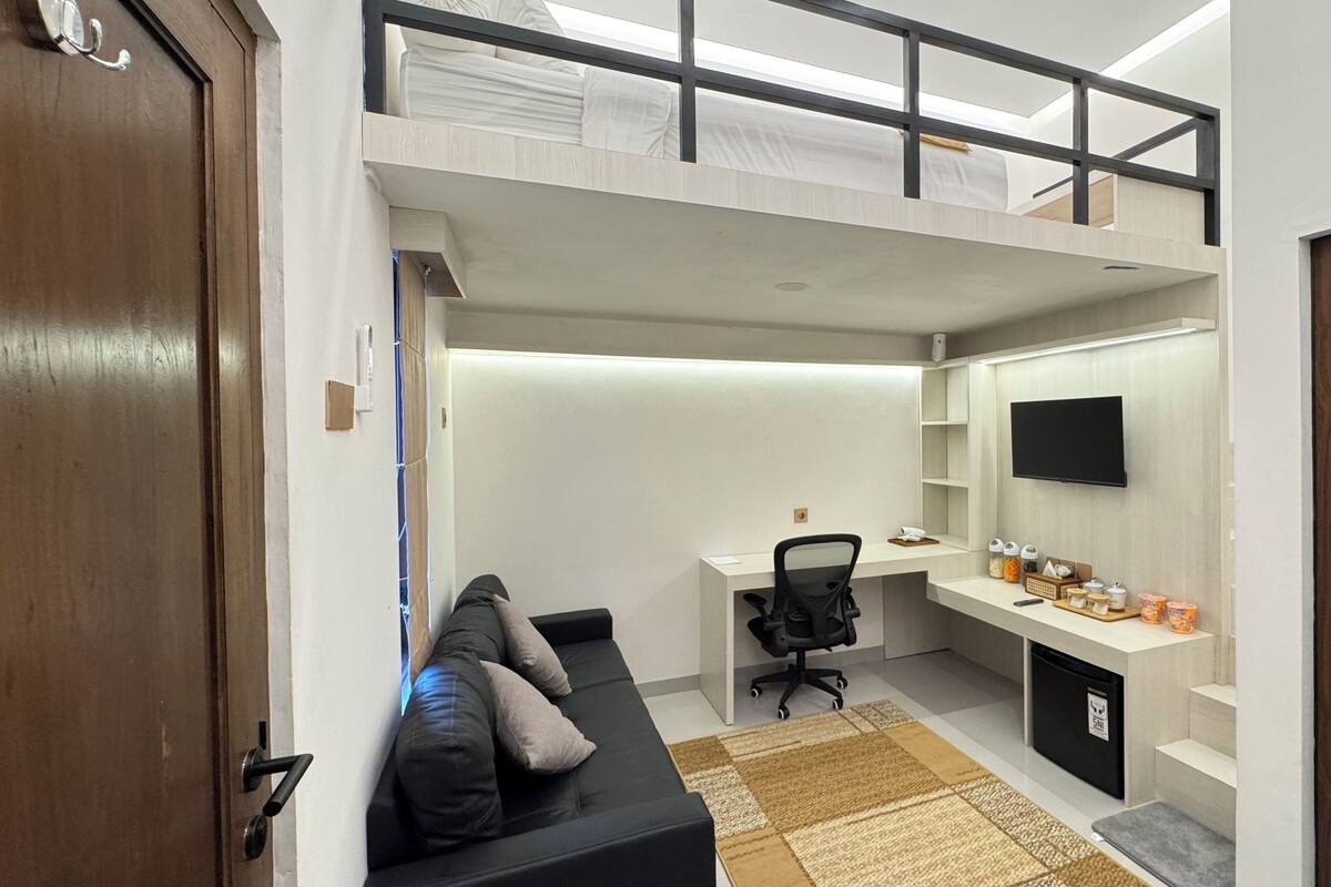 Ein kompaktes Studioapartment mit Schlafplatz in der Schlafgalerie, einer kleinen Arbeitsnische und einer Küchenzeile.