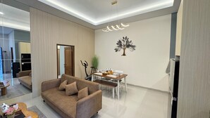 A modern living room with a sofa, dining table, and a decorative tree wall art. - D' Mangkuyudan Luxury Guest House (Yogyakarta)