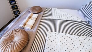 En snyggt bäddad säng med randiga sängkläder, en hoprullad handduk och dekorativa kuddar.