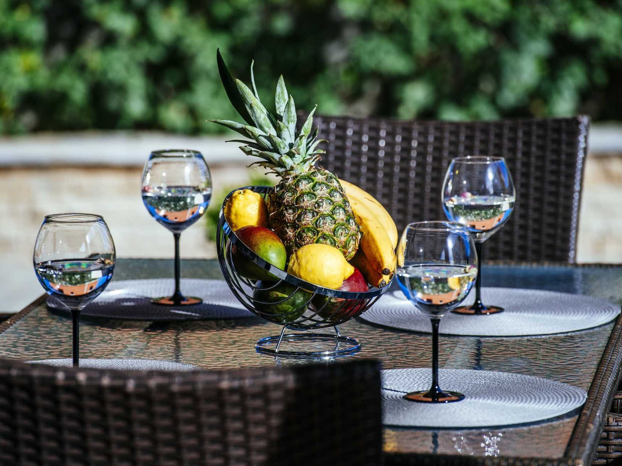 A table with a fruit bowl and wine glasses.