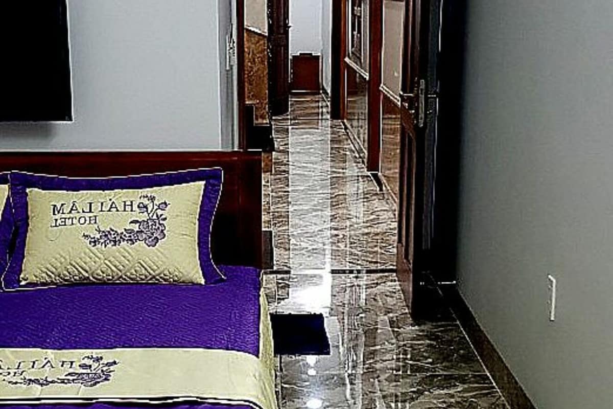 Un corridoio d'hotel con un letto, un pavimento in marmo e una porta che dà su un'altra stanza.