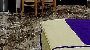 Una habitación con una cama, una mesa con dos sillas, una botella de agua y una puerta.