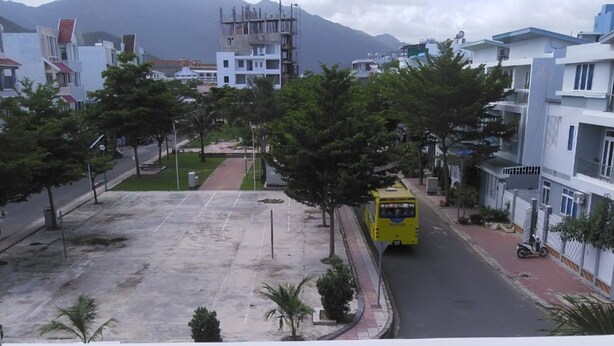 Un autobús amarillo en una calle de la ciudad, con edificios modernos y una montaña al fondo.