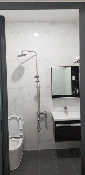 Un bagno con doccia, toilette, lavandino e specchio.