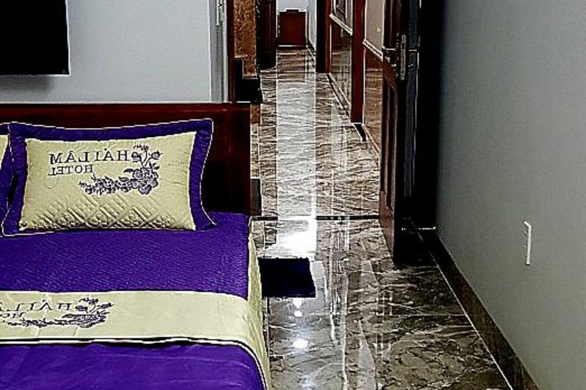 A hotel hallway with a bed, a marble floor, and a door leading to another room.