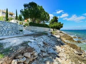 A coastal property with a stone wall, a paved pathway, and a view of the sea. - Beachfront Villa Mediterranea with pool by Interhome (Ugljan/Kukljica)