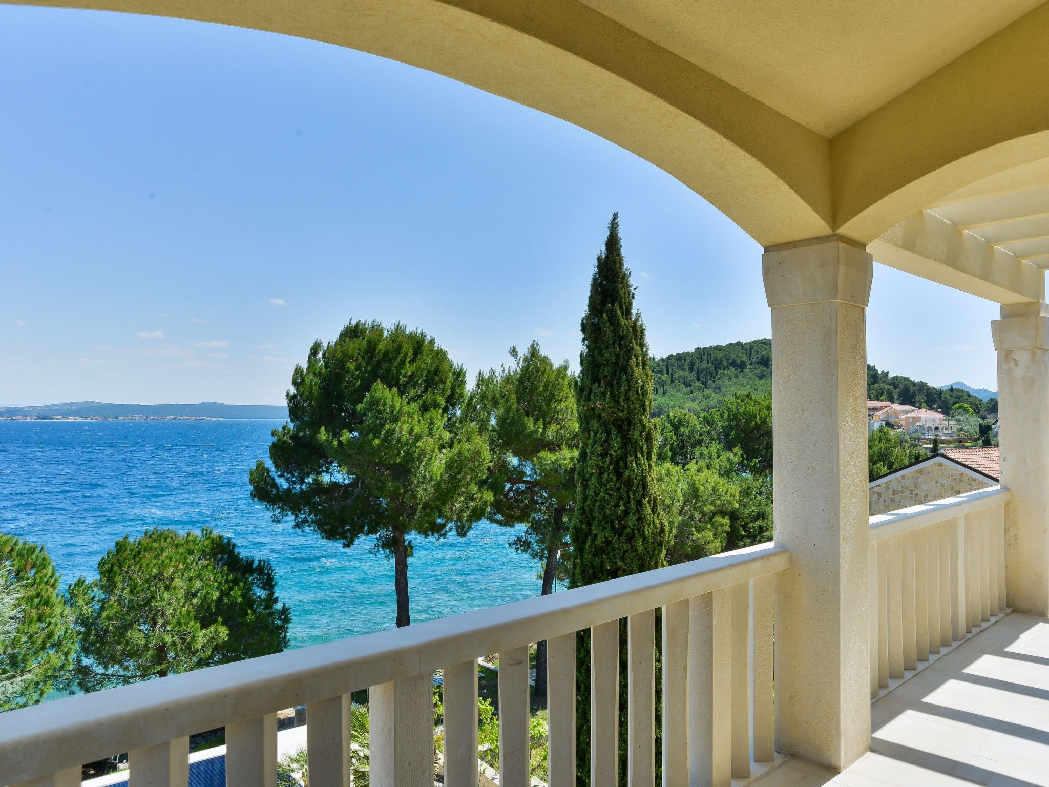 A balcony with a view of the sea and trees.