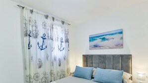 Ein Hotelzimmer mit Bett, einem Meeresbild und Vorhängen mit maritimem Dekor.