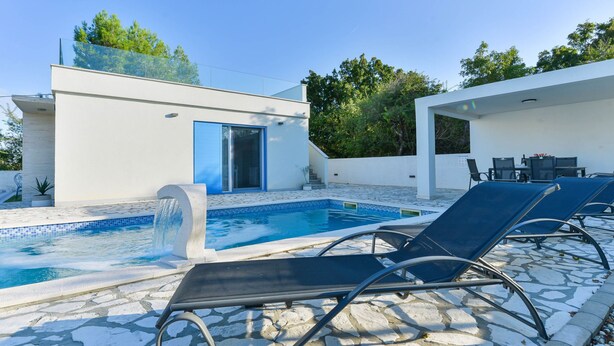 Ein moderner Poolbereich im Freien mit Liegestühlen und einem kleinen Gebäude mit einer blauen Tür.