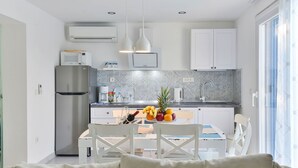 Eine moderne Küche mit weißen Schränken, einem Edelstahl-Kühlschrank und einem Essbereich mit Tisch für zwei Personen.