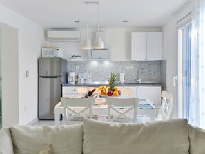 Cozinha moderna com armários brancos, geladeira de aço inoxidável e área de jantar com mesa posta para dois.