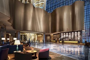 A spacious lobby with a high ceiling, a reception desk, seating area, and a large glass wall. - Wyndham Grand Foshan Gaoming (Foshan)
