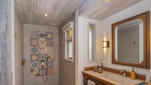 A bathroom with a shower, a large mirror, and a vanity with a sink. - Sudamala Resort, Seraya (Labuan Bajo)