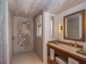 A bathroom with a shower, a large mirror, and a vanity with a sink.