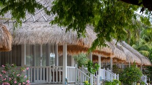 A resort with thatched-roof structures, white railings, and a stone wall. - Sudamala Resort, Seraya (Labuan Bajo)
