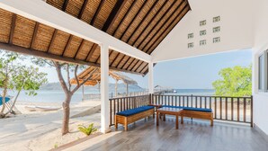 A covered outdoor seating area with a view of the sea and a boat dock. - Sudamala Resort, Seraya (Labuan Bajo)