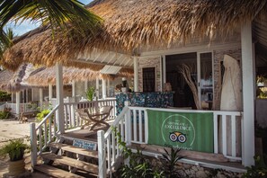 A beachfront property with thatched roofs, wooden deck, and a green banner indicating a certification. - Sudamala Resort, Seraya (Labuan Bajo)