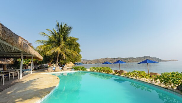 A poolside area with a thatched-roof structure, lounge chairs, and umbrellas. - Sudamala Resort, Seraya (Labuan Bajo)