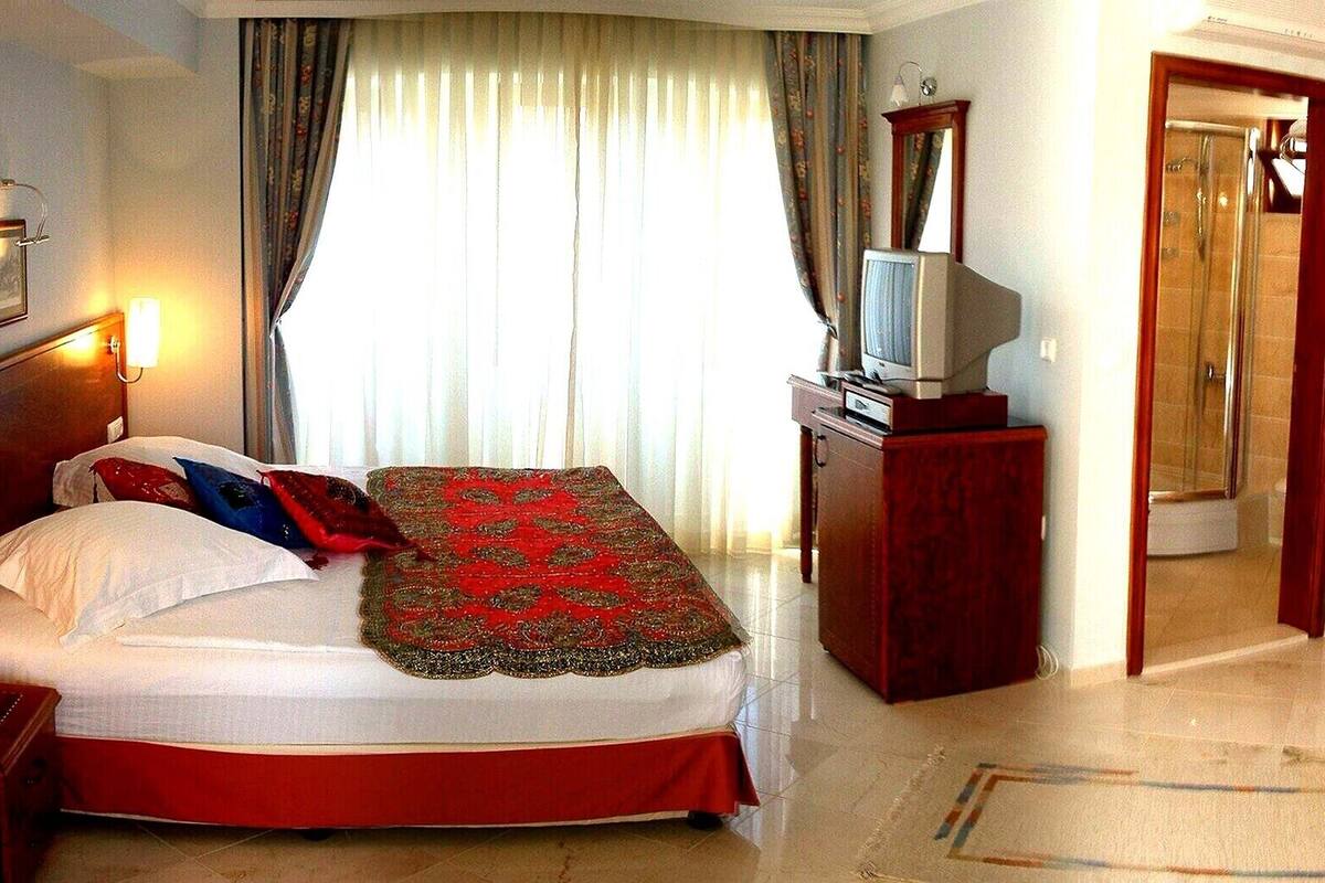 Ein Hotelzimmer mit Bett, Fernseher, Schreibtisch und Dusche.