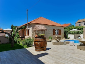 A house with a red-tiled roof, a stone exterior, a wooden barrel planter, a pool, and outdoor furniture. - Modern Holiday house Gatsby only 40m from the sea by Interhome (Petrčane)