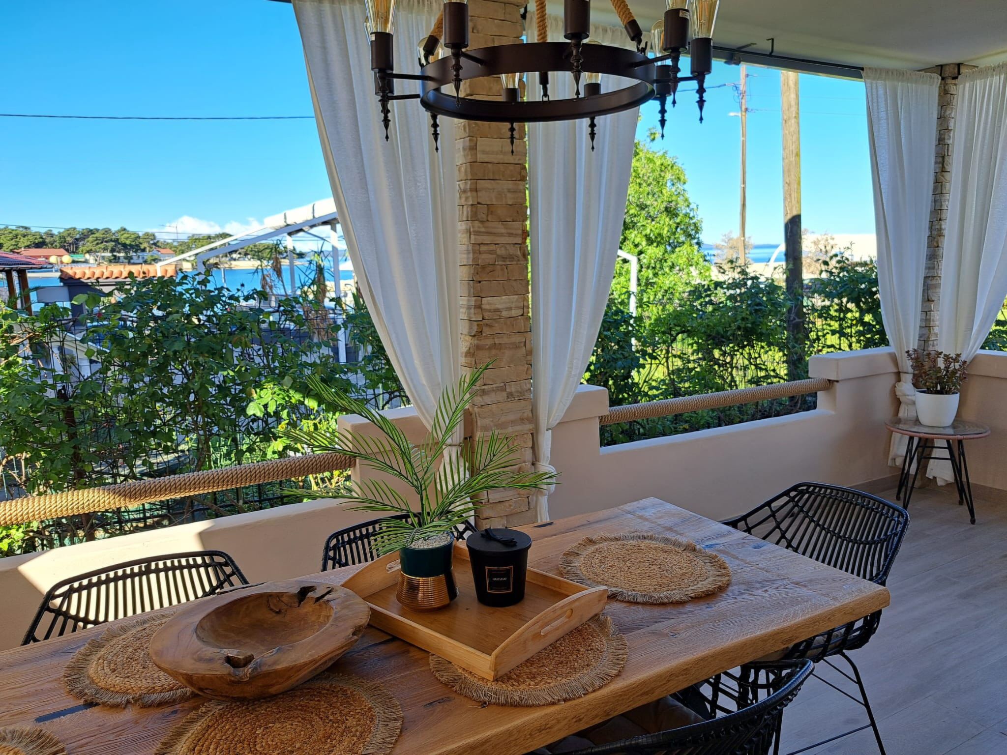 An outdoor patio with a wooden table, chairs, and a hanging light fixture.