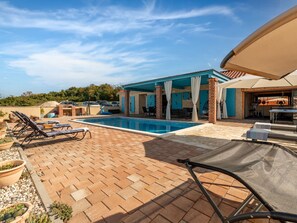 A pool area with lounge chairs, a covered patio, and a brick pathway. - Villa Jurenda with heated pool by Interhome (Debeljak)
