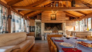 Ein gemütliches Interieur mit Holzbalkendecke, Kamin, Essbereich mit gedecktem Tisch und einer Sitzecke.
