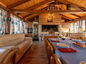 Ein gemütliches Interieur mit Holzbalkendecke, Kamin, Essbereich mit gedecktem Tisch und einer Sitzecke.